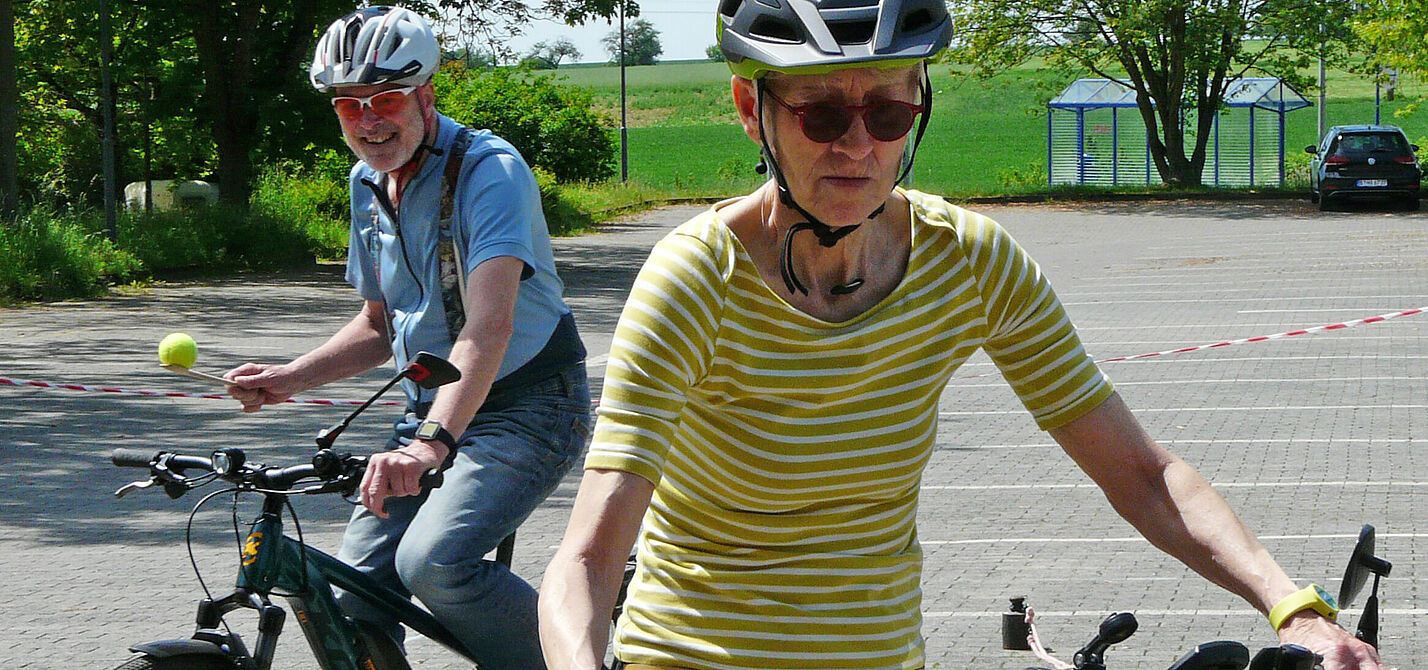 Balancieren beim FahrSicherheitsTraining Zwei Radfahrende balancieren mit Bällen