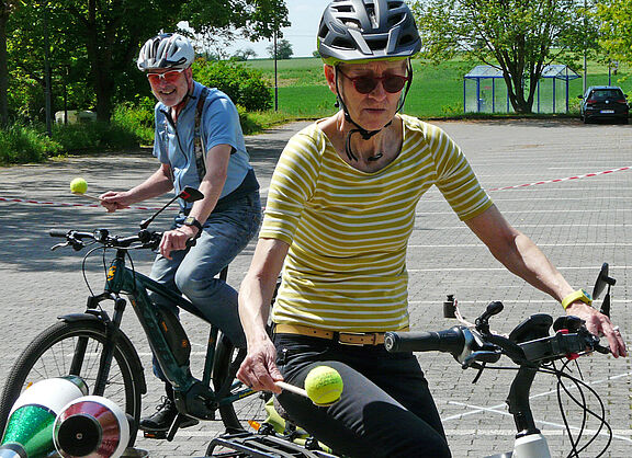 Balancieren beim FahrSicherheitsTraining Zwei Radfahrende balancieren mit Bällen