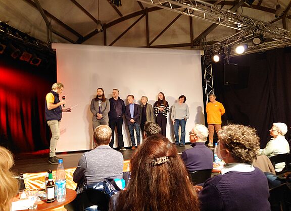 8 Personen auf einer Bühne